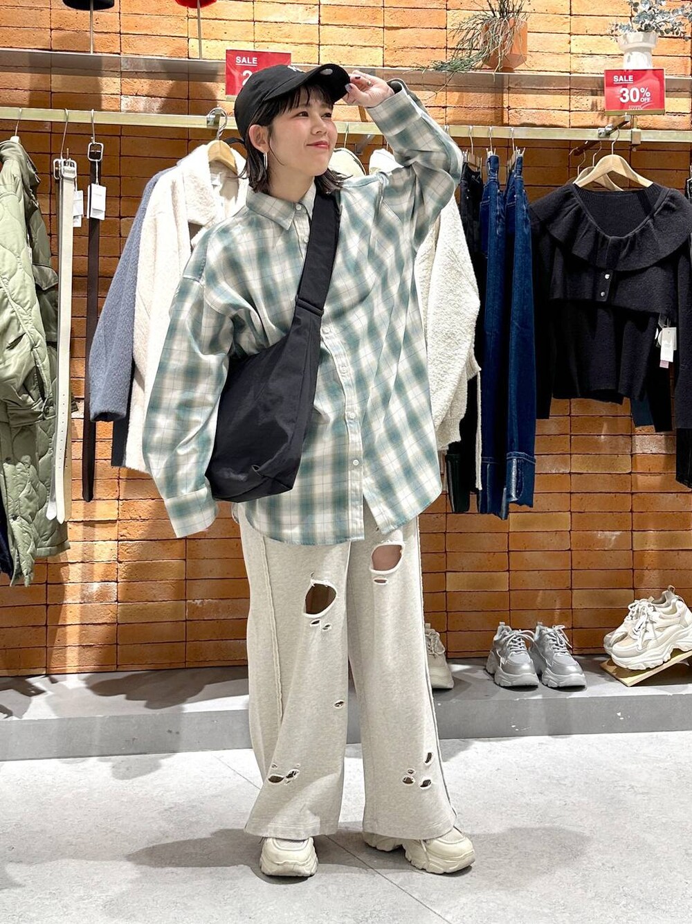 ブラック系のショルダーバッグ、ホワイト系のスニーカー、グリーン系のシャツ/ブラウスを着用したレディースの冬コーディネートの1枚目の写真