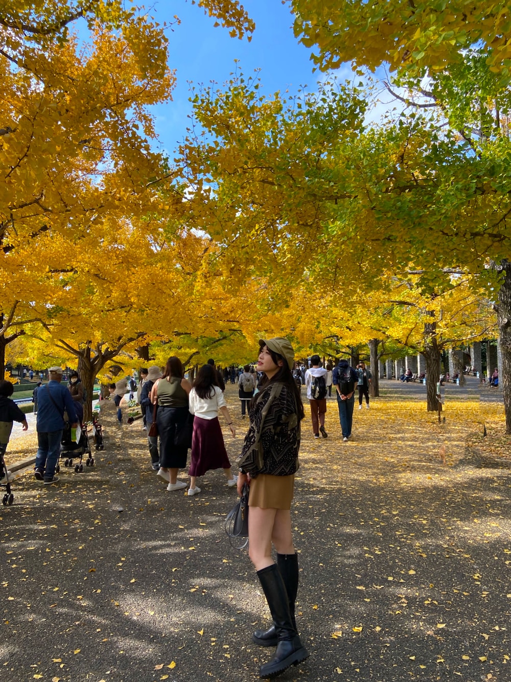 ブラック系のブーツ、ブルー系のハンドバッグ、ベージュ系のキャスケットを着用したレディースの秋コーディネートの1枚目の写真