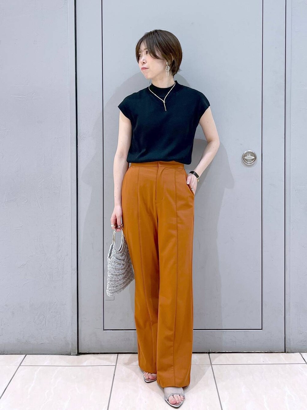 ブラック系のニット/セーター、シルバー系のハンドバッグ、シルバー系のサンダルを着用したレディースの夏コーディネートの1枚目の写真