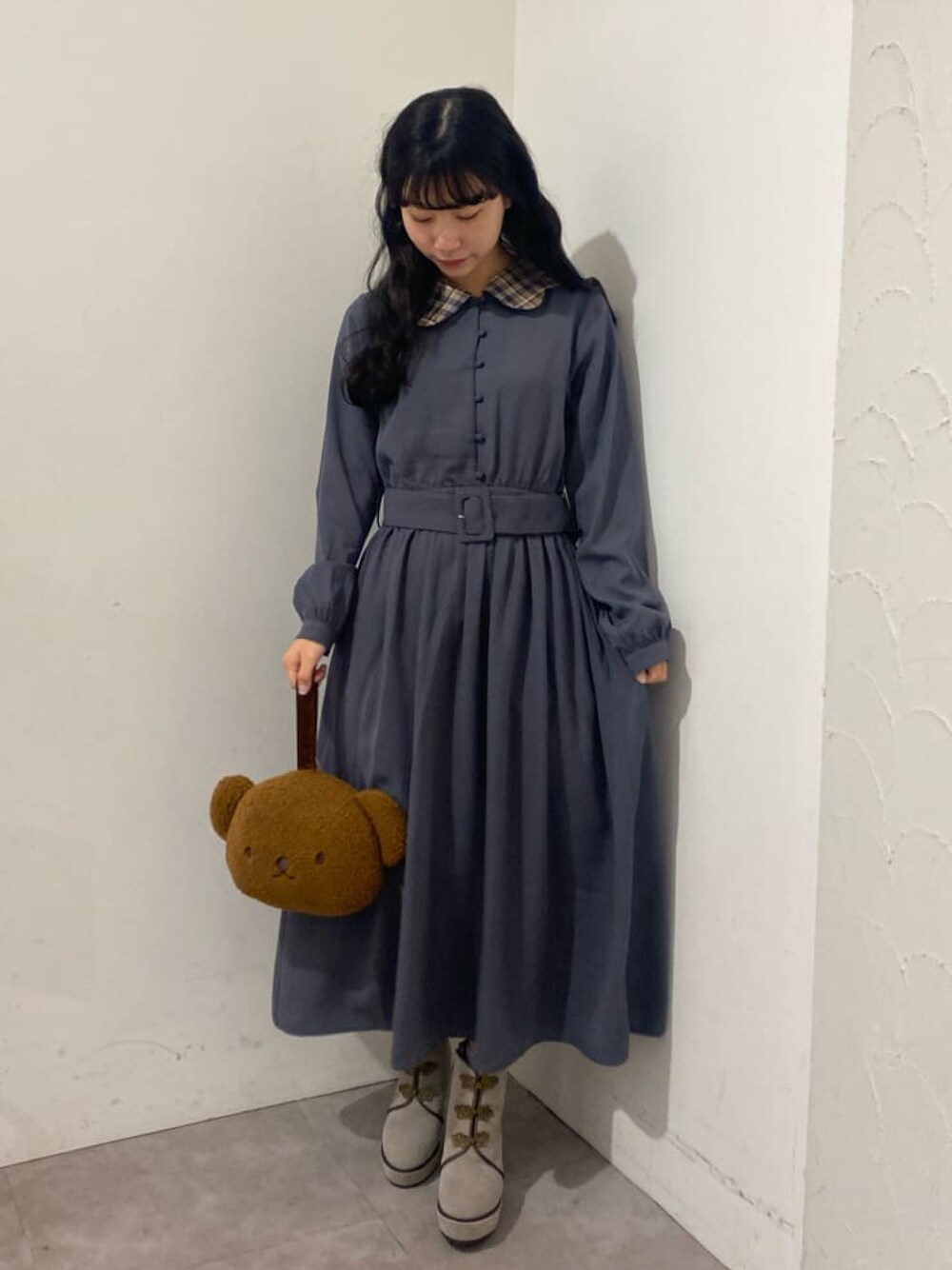 ブルー系のワンピース、ブラウン系のハンドバッグ、ベージュ系のブーツを着用したレディースの冬コーディネートの1枚目の写真