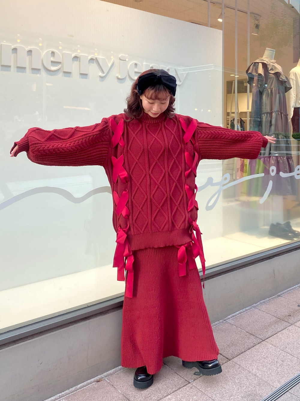 レッド系のニット/セーター、レッド系のスカート、ブラック系のローファーを着用したレディースの秋コーディネートの1枚目の写真