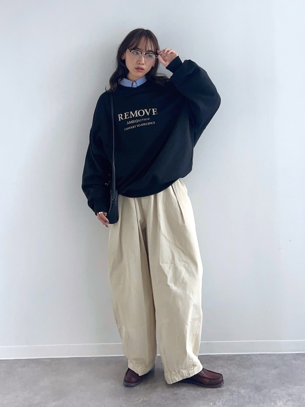 ブラック系のスウェット、ベージュ系のチノパンツ、ブラウン系のローファーを着用したレディースの冬コーディネートの1枚目の写真