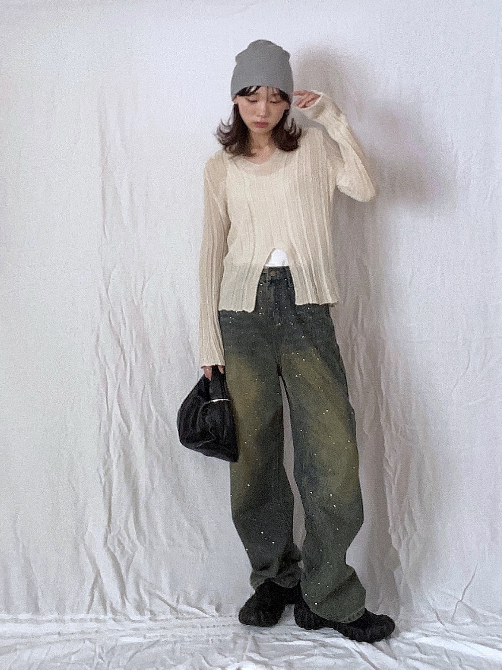 ベージュ系のニット/セーター、ブルー系のデニムパンツ、ブラック系のスニーカーを着用したレディースの春コーディネートの1枚目の写真