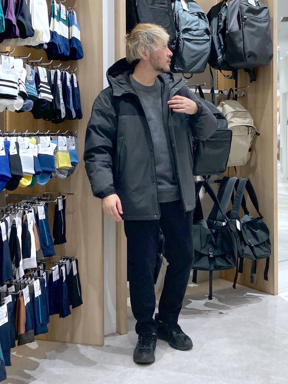 グレー系のダウンジャケット/コート、グレー系のニット/セーター、ブラック系のその他パンツを着用したメンズの秋コーディネートの1枚目の写真