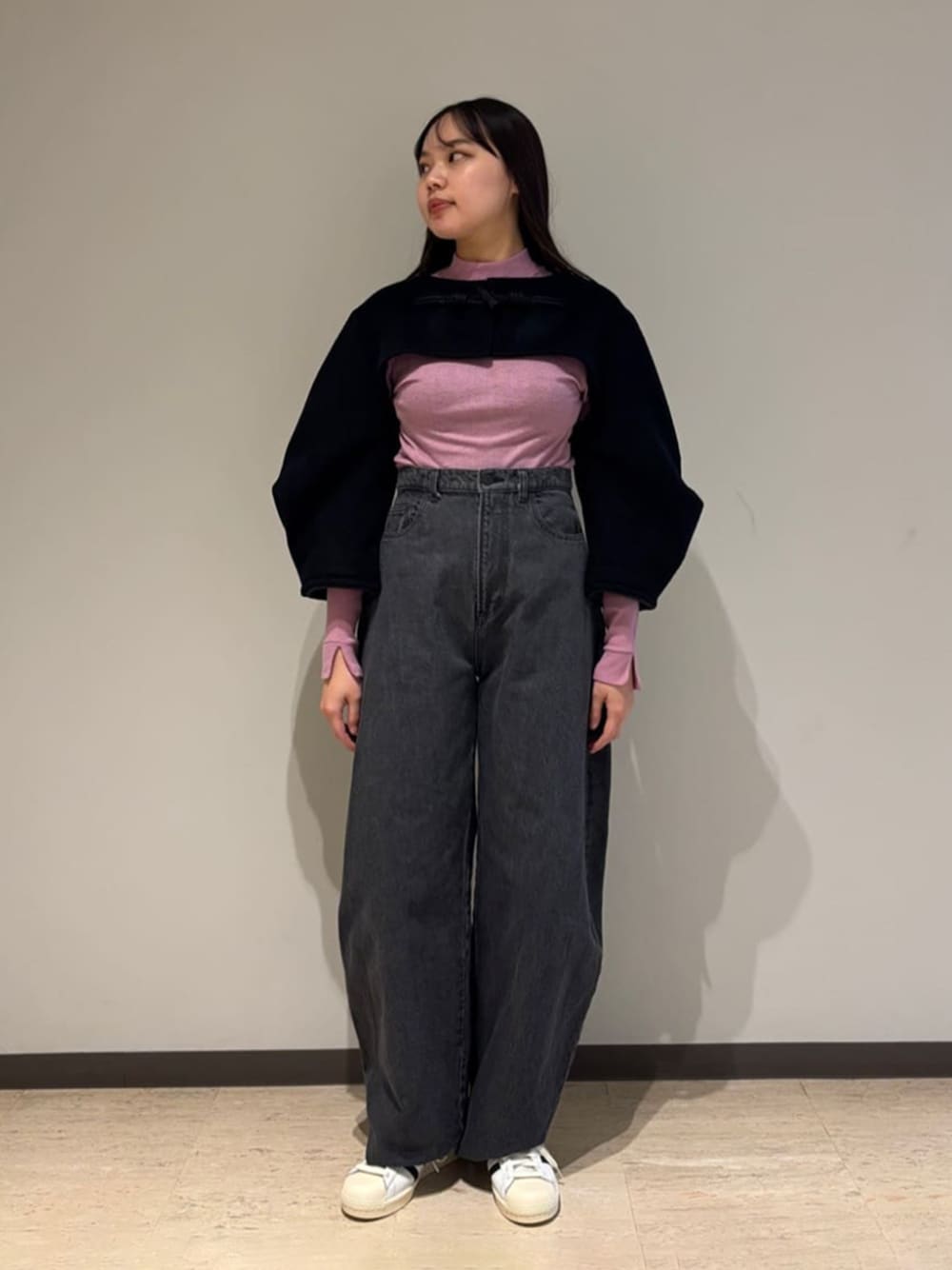 ホワイト系のスニーカー、ブラック系のその他アウターを着用したレディースの春コーディネートの1枚目の写真