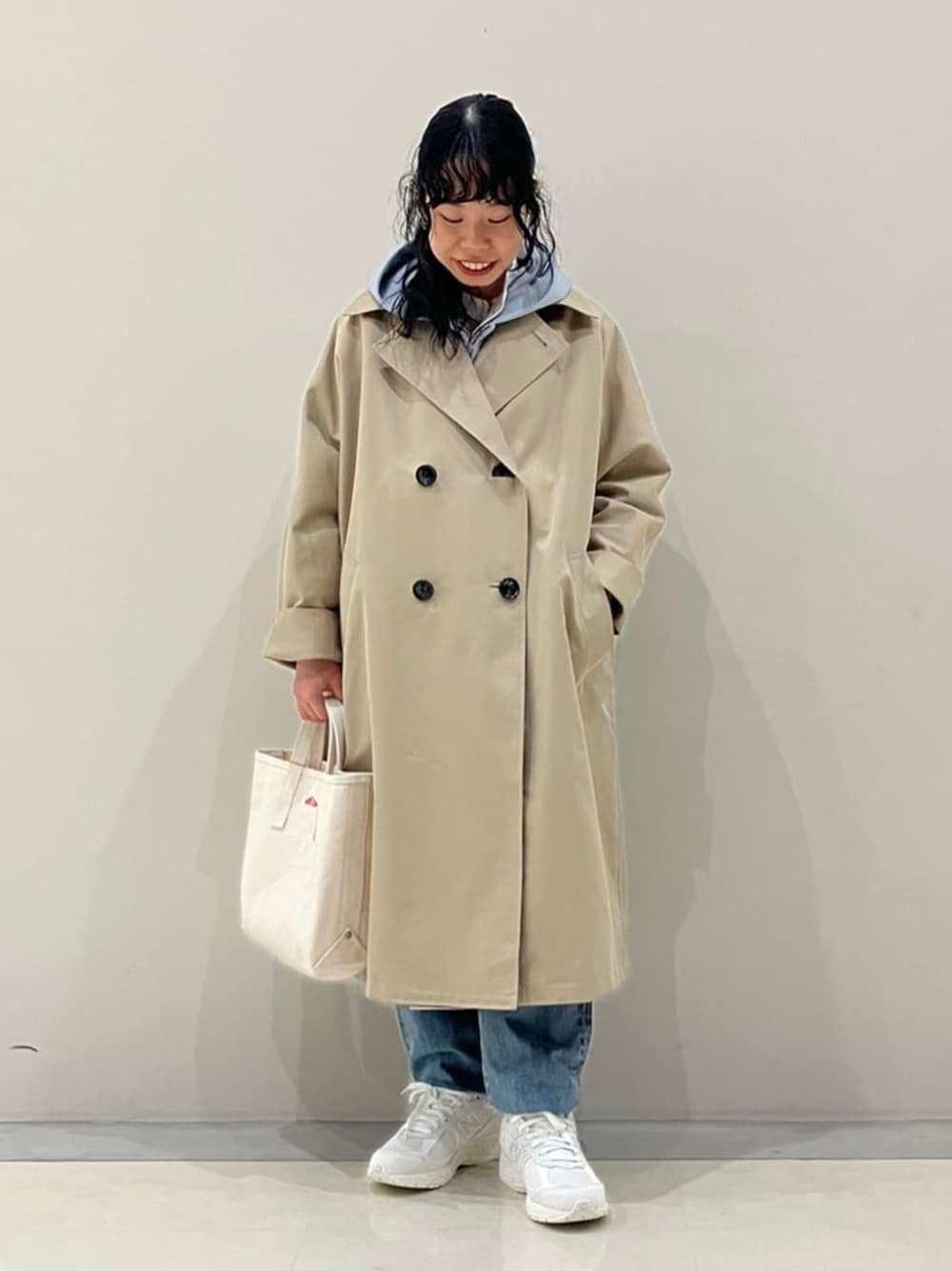 ベージュ系のトレンチコート、ホワイト系のスニーカー、ホワイト系のトートバッグを着用したレディースの春コーディネートの1枚目の写真