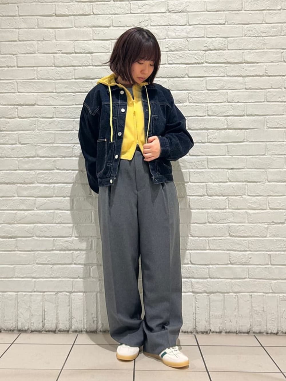 イエロー系のパーカー、ホワイト系のスニーカーを着用したレディースの春コーディネートの1枚目の写真