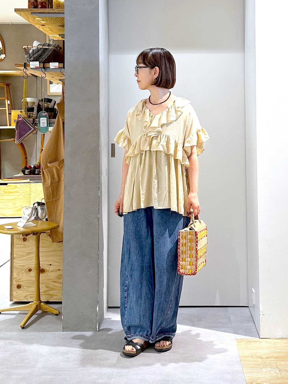 ブルー系のデニムパンツ、ベージュ系のシャツ/ブラウス、イエロー系のかごバッグを着用したレディースの夏コーディネートの1枚目の写真
