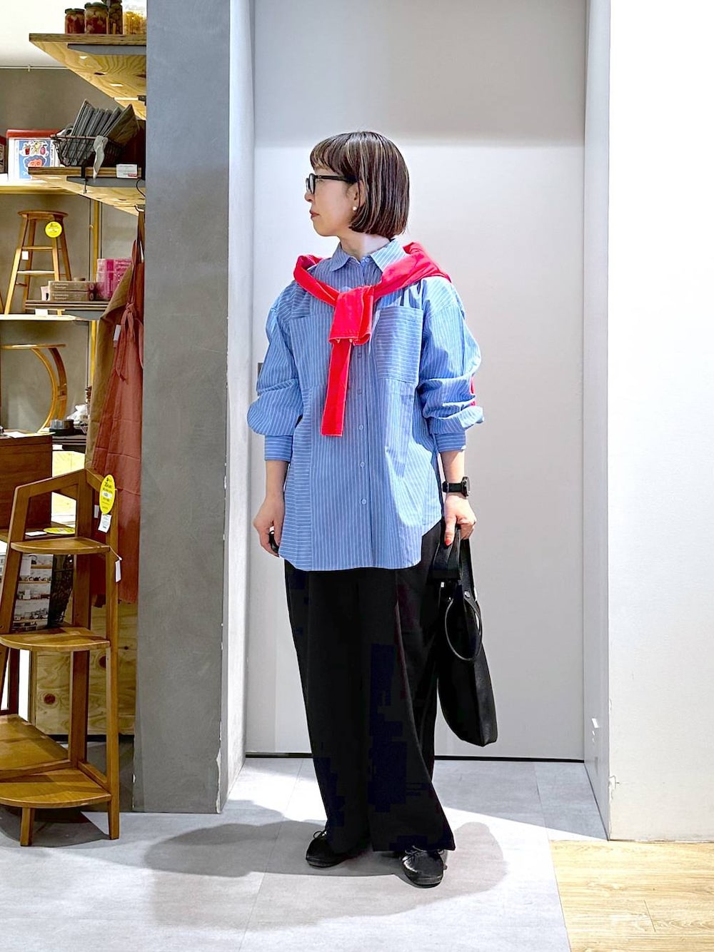 ブラック系のトートバッグ、ブラック系のスラックス、ブルー系のシャツ/ブラウスを着用したレディースの春コーディネートの1枚目の写真