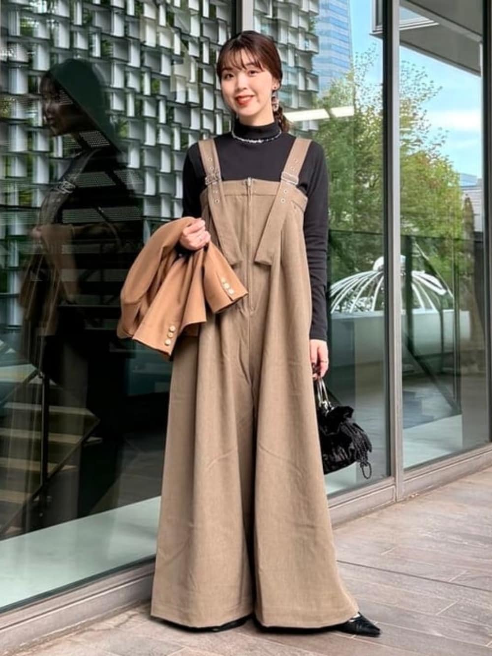 ブラック系のショルダーバッグ、ブラウン系のサロペット/オーバーオール、ブラック系のTシャツ/カットソーを着用したレディースの秋コーディネートの1枚目の写真