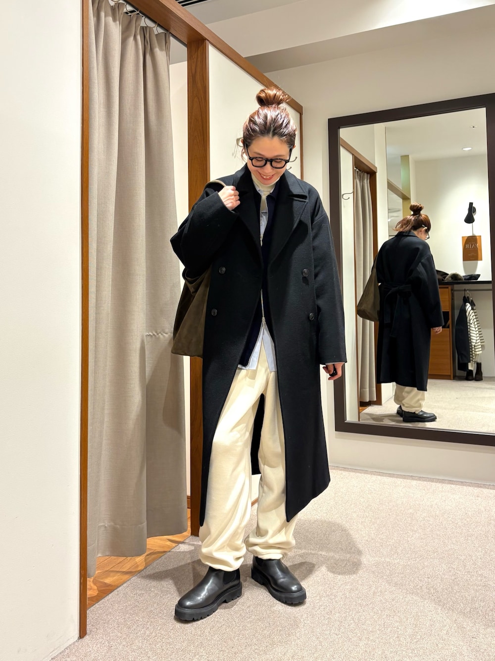 ブラック系のチェスターコート、ホワイト系のその他パンツ、ブラック系のブーツを着用したレディースの冬コーディネートの1枚目の写真