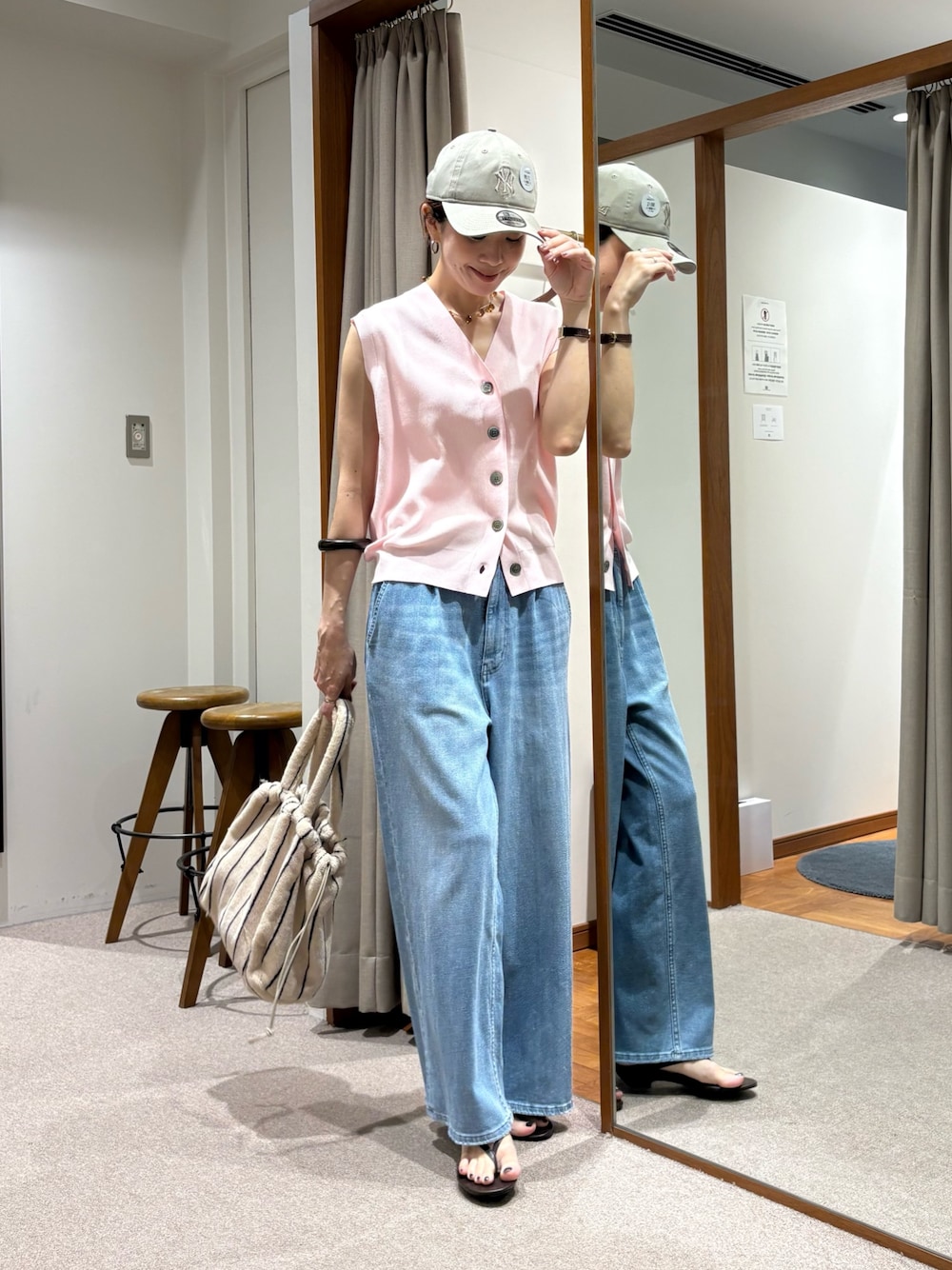 ブルー系のデニムパンツ、ピンク系のベスト、ホワイト系のハンドバッグを着用したレディースの夏コーディネートの1枚目の写真