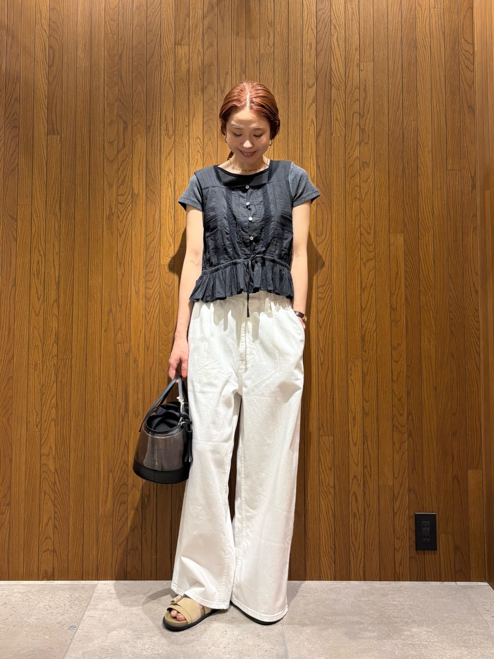 ホワイト系のデニムパンツ、ベージュ系のサンダル、ブラック系のかごバッグを着用したレディースの夏コーディネートの1枚目の写真
