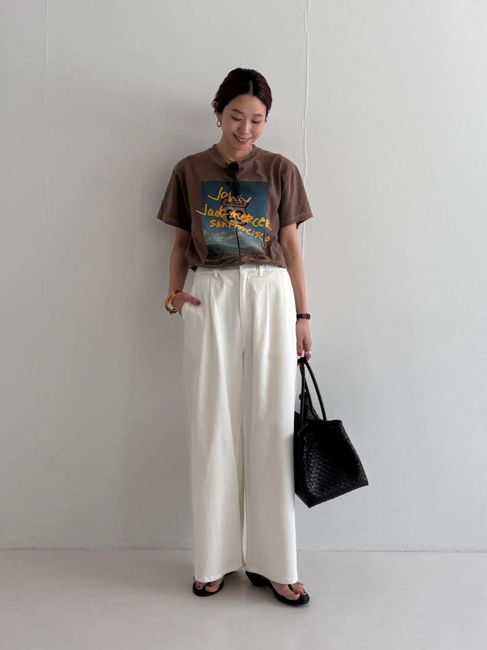 ホワイト系のデニムパンツ、ブラウン系のTシャツ/カットソー、ブラック系のサンダルを着用したレディースの春コーディネートの1枚目の写真