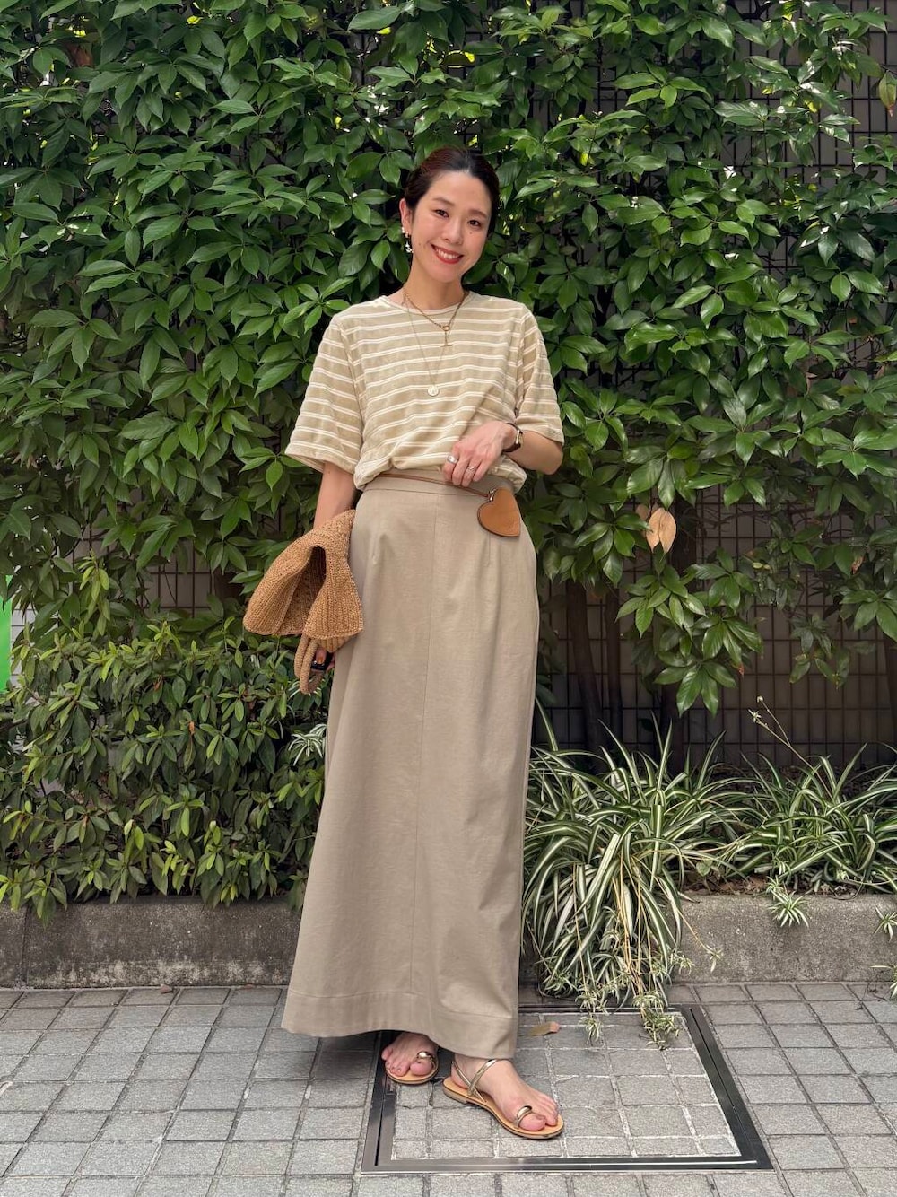 ベージュ系のスカート、ゴールド系のサンダルを着用したレディースの夏コーディネートの1枚目の写真