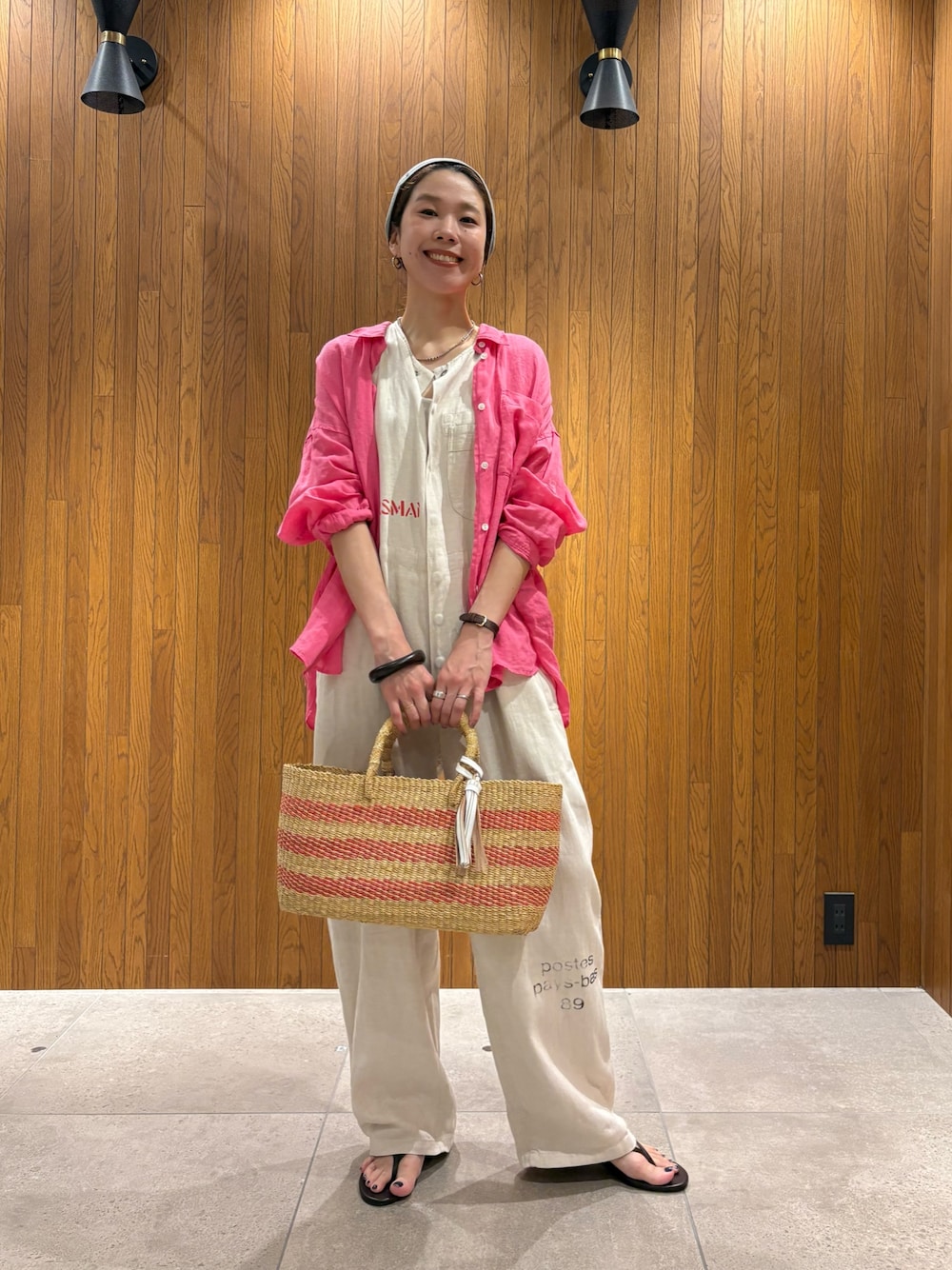 ベージュ系のその他パンツ、ベージュ系のかごバッグ、ブラウン系のサンダルを着用したレディースの夏コーディネートの1枚目の写真