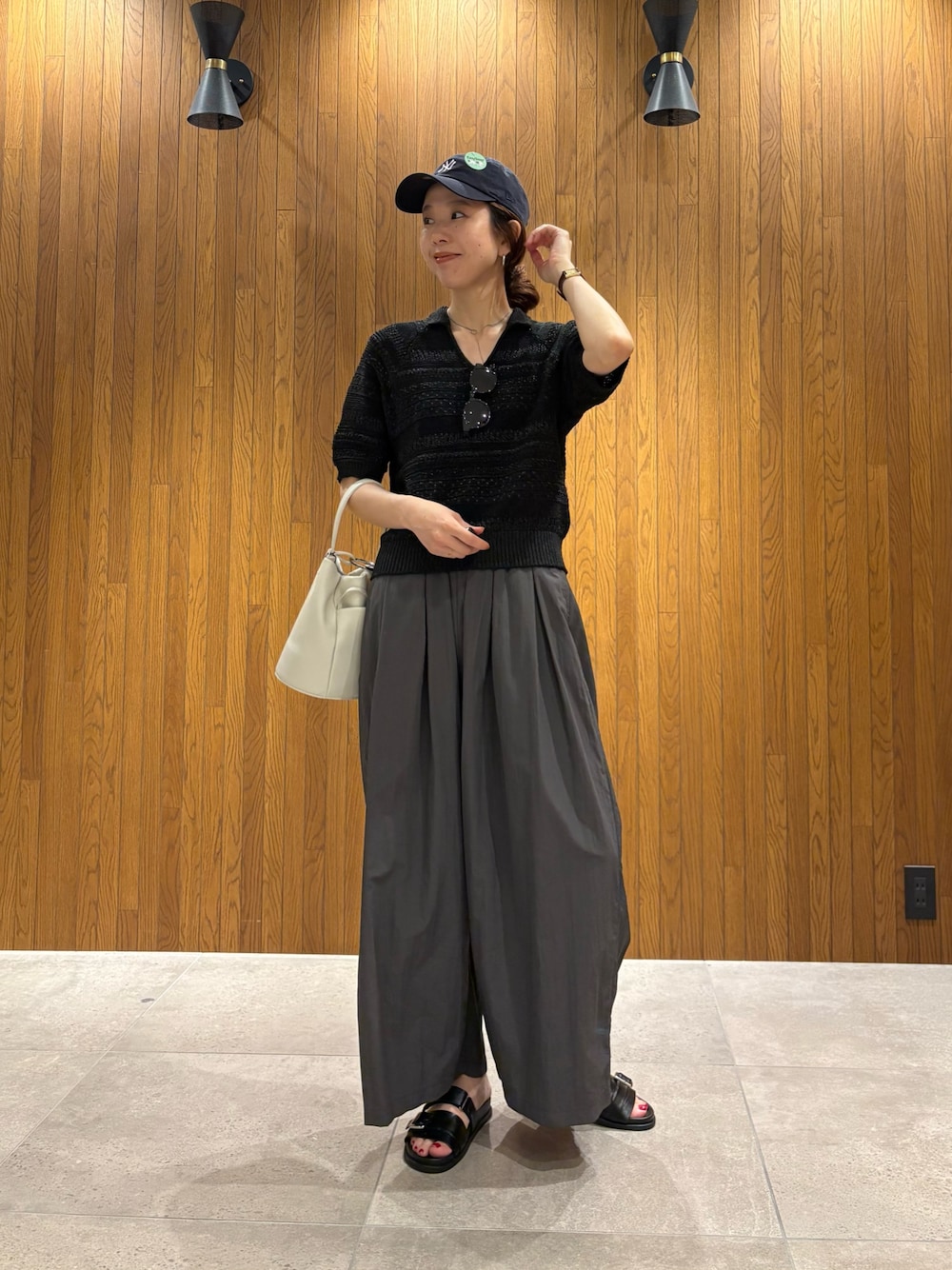 グレー系のその他パンツ、ブラック系のニット/セーター、ホワイト系のハンドバッグを着用したレディースの春コーディネートの1枚目の写真