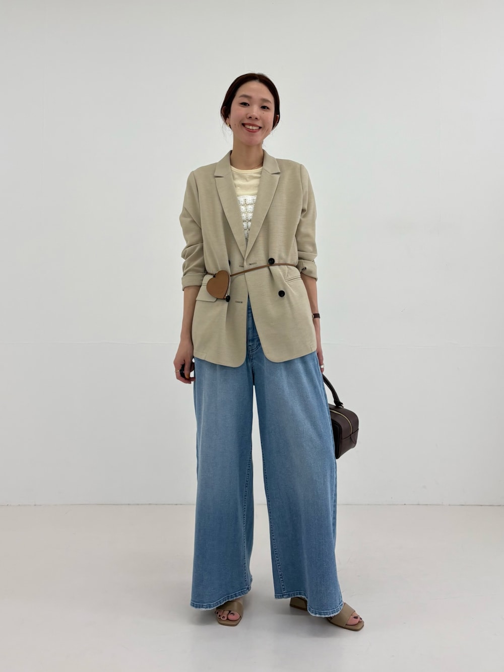 ベージュ系のその他アウター、イエロー系のTシャツ/カットソー、ブルー系のデニムパンツを着用したレディースの春コーディネートの1枚目の写真