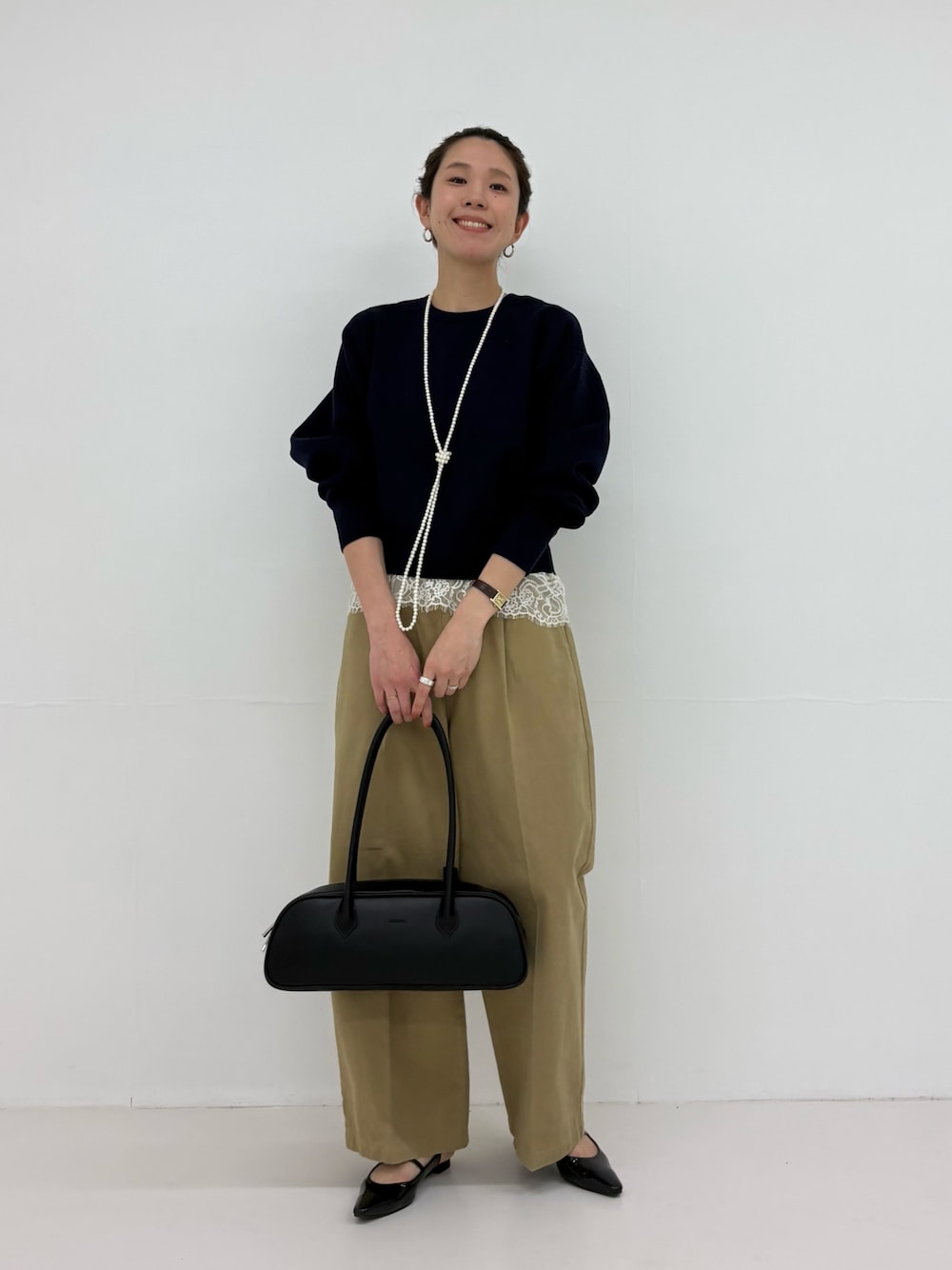 ブラック系のパンプス、ブルー系のニット/セーター、ベージュ系のその他パンツを着用したレディースの冬コーディネートの1枚目の写真