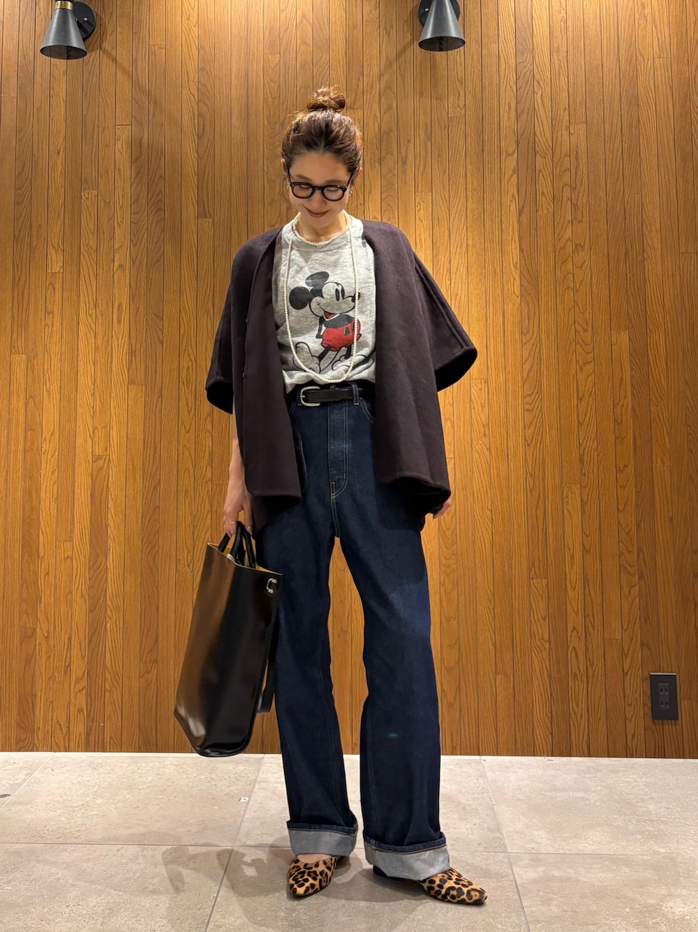 レッド系のポンチョ、ブルー系のデニムパンツ、ブラック系のトートバッグを着用したレディースの秋コーディネートの1枚目の写真