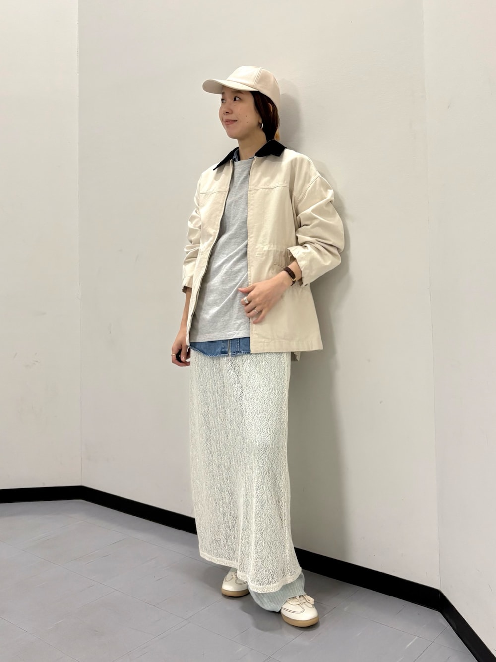 ベージュ系のカバーオール、ホワイト系のスカート、ホワイト系のスニーカーを着用したレディースの冬コーディネートの1枚目の写真