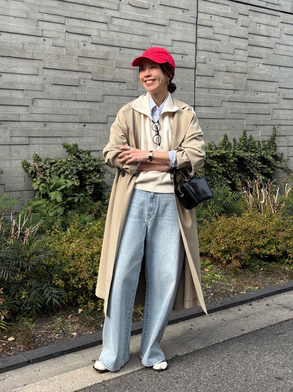 ベージュ系のトレンチコート、グレー系のデニムパンツ、ブラック系のショルダーバッグを着用したレディースの冬コーディネートの1枚目の写真