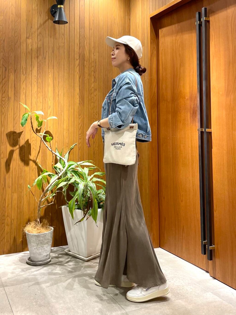 グリーン系のスカート、ブルー系のデニムジャケット、ホワイト系のスニーカーを着用したレディースの秋コーディネートの1枚目の写真