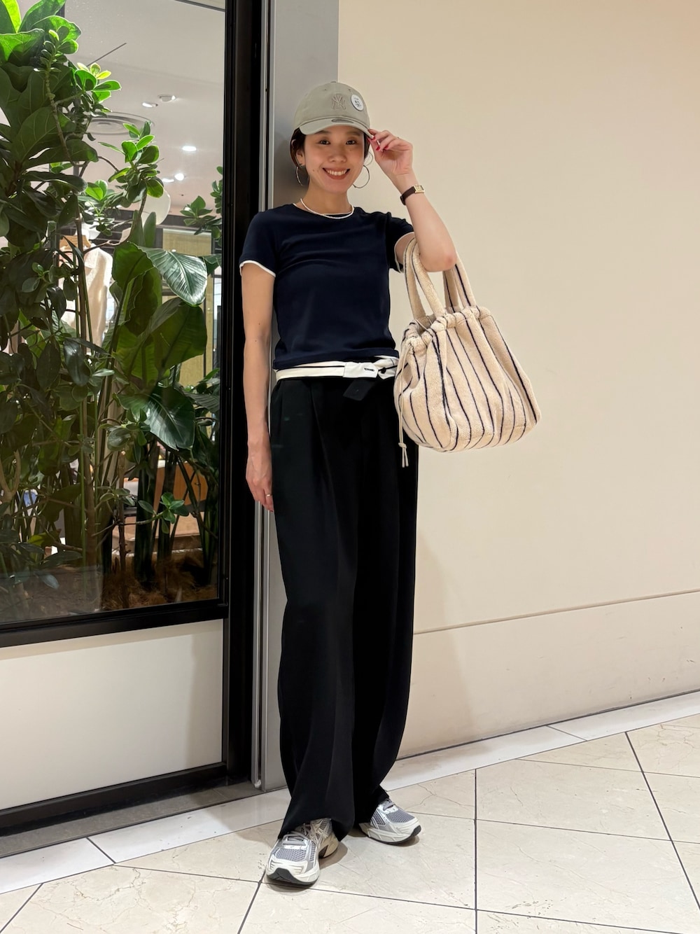 ブラック系のその他パンツ、グレー系のスニーカー、ホワイト系のハンドバッグを着用したレディースの夏コーディネートの1枚目の写真