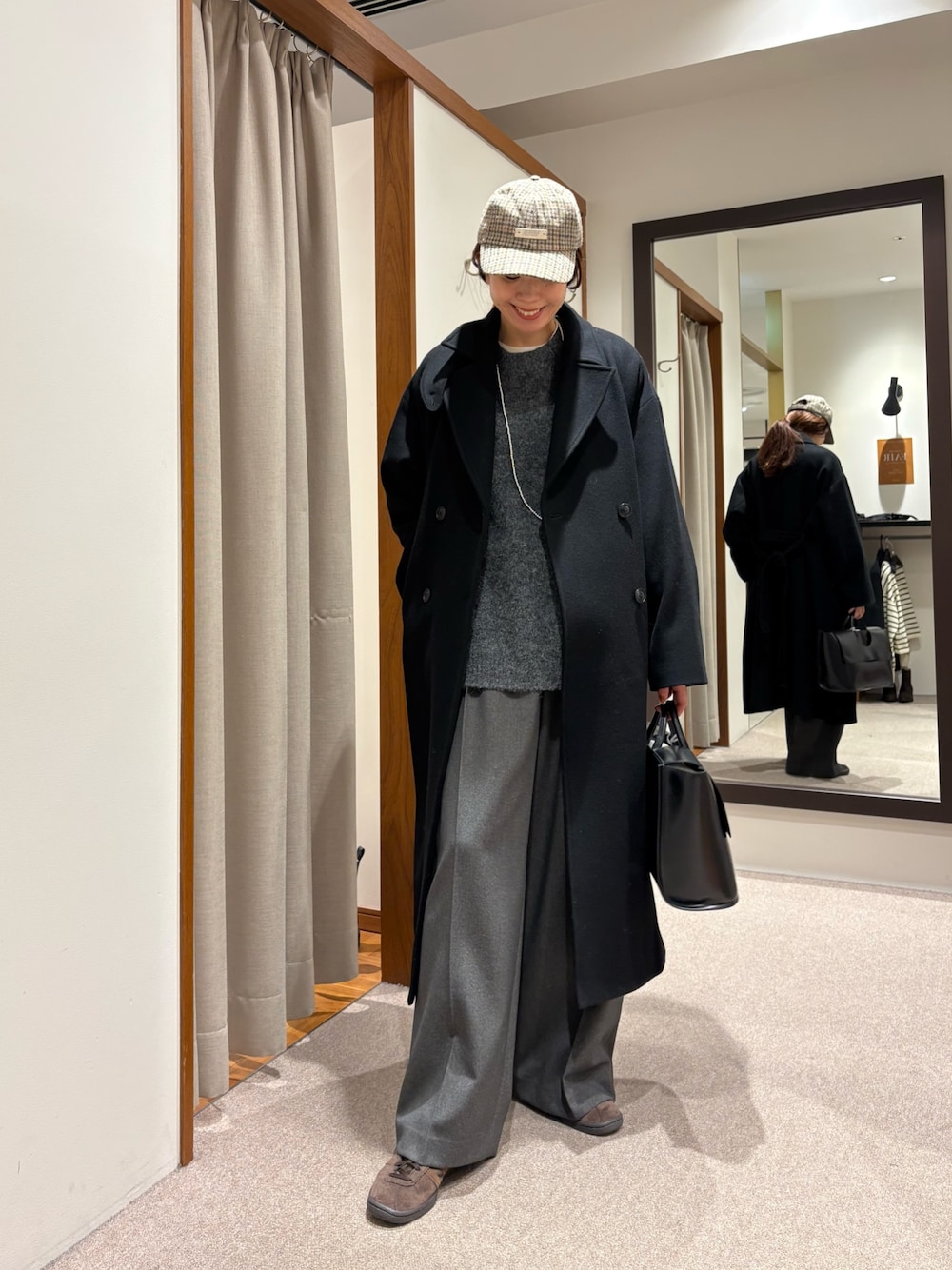 ブラック系のチェスターコート、グレー系のその他パンツ、ブラック系のハンドバッグを着用したレディースの冬コーディネートの1枚目の写真