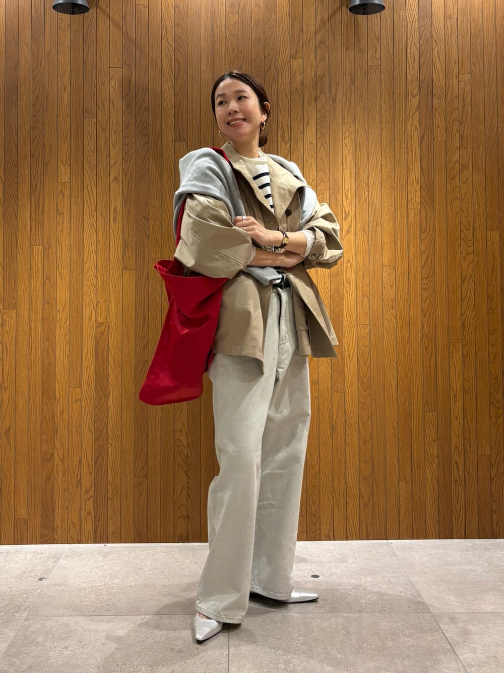 ベージュ系のトレンチコート、グレー系のデニムパンツ、シルバー系のパンプスを着用したレディースの冬コーディネートの1枚目の写真