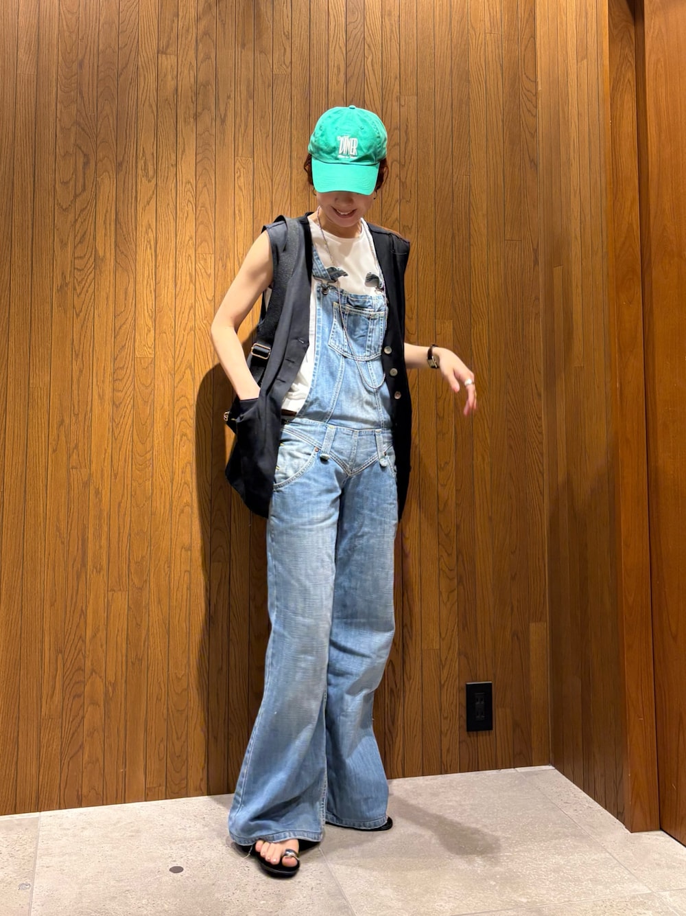 ブラック系のダウンベスト、ブラック系のショルダーバッグ、ホワイト系のTシャツ/カットソーを着用したレディースの夏コーディネートの1枚目の写真