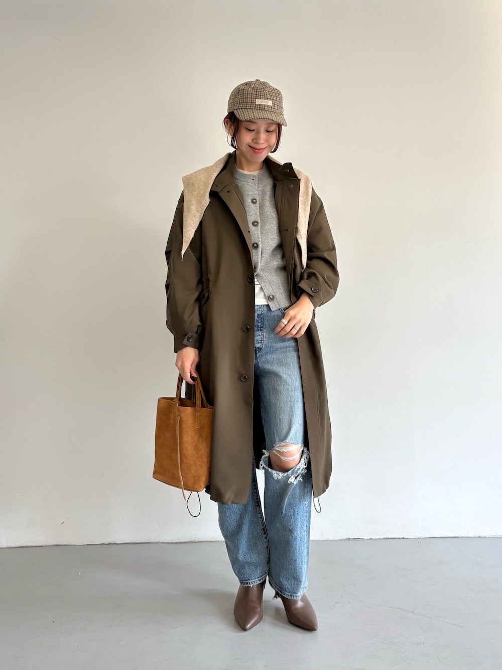 ブルー系のデニムパンツ、ベージュ系のトートバッグ、ホワイト系のTシャツ/カットソーを着用したレディースの冬コーディネートの1枚目の写真