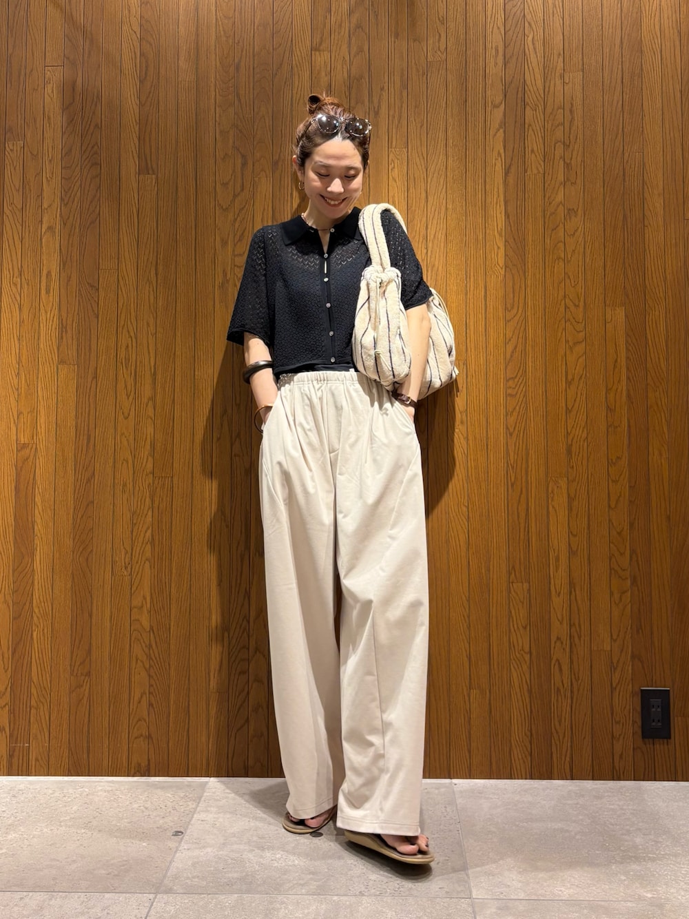 ブラック系のニット/セーター、ホワイト系のその他パンツ、ホワイト系のハンドバッグを着用したレディースの春コーディネートの1枚目の写真