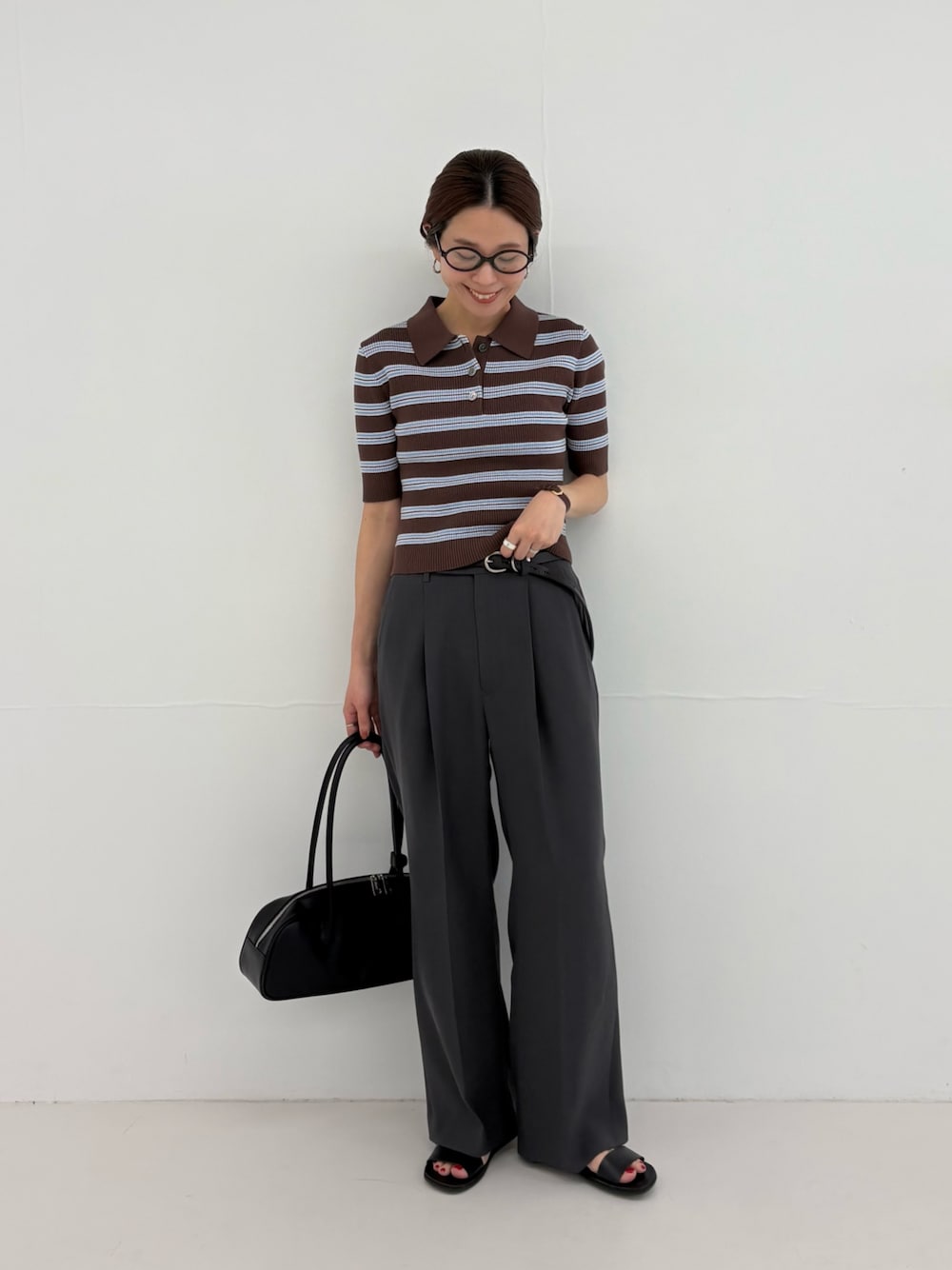 グレー系のその他パンツ、ブラウン系のニット/セーター、ブラック系のショルダーバッグを着用したレディースの春コーディネートの1枚目の写真