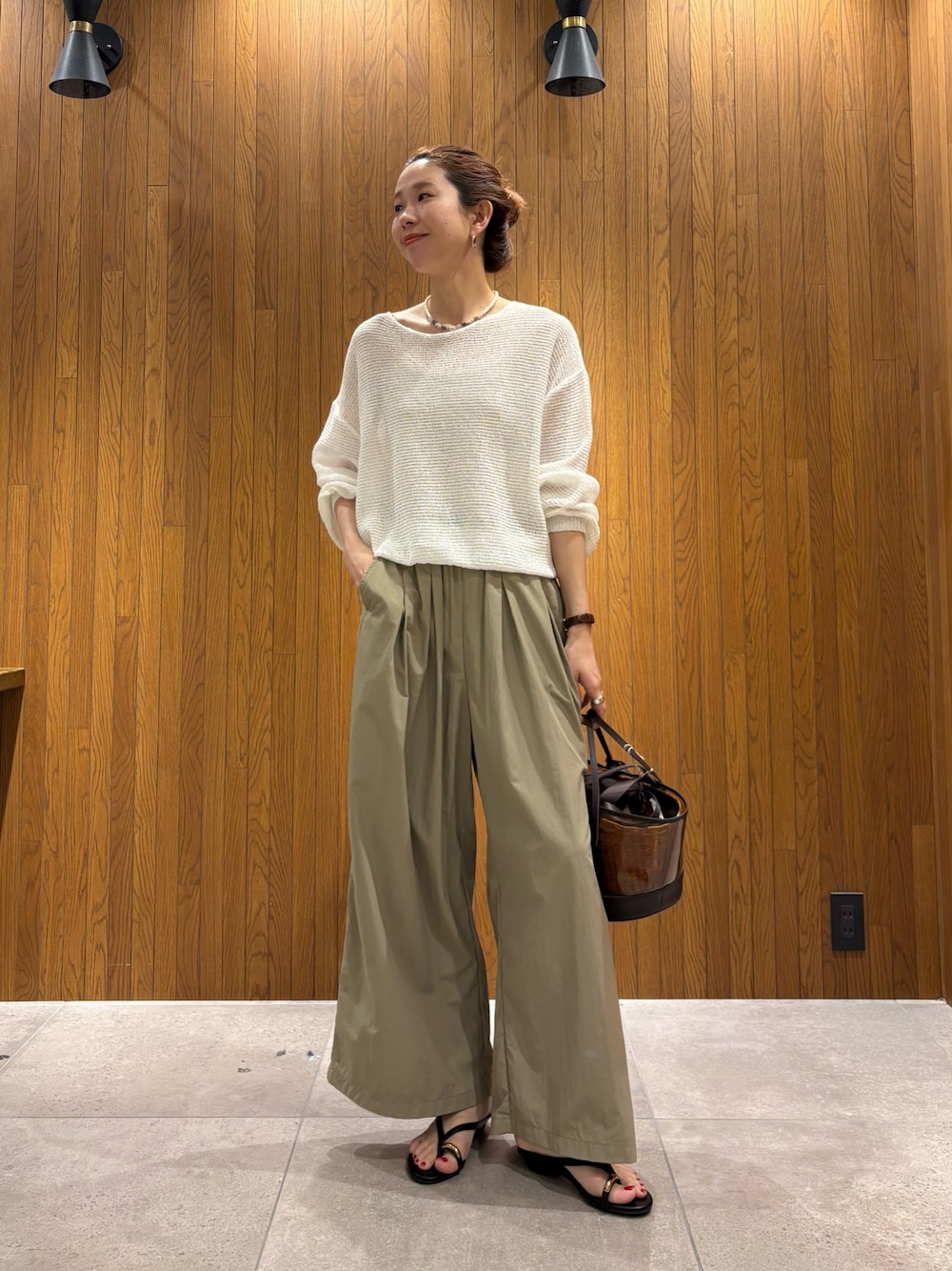 ホワイト系のニット/セーター、ベージュ系のその他パンツ、ブラウン系のかごバッグを着用したレディースの春コーディネートの1枚目の写真