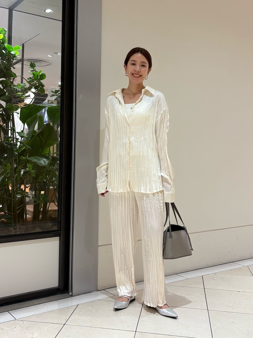 グレー系のハンドバッグ、シルバー系のパンプス、ホワイト系のキャミソールを着用したレディースの春コーディネートの1枚目の写真
