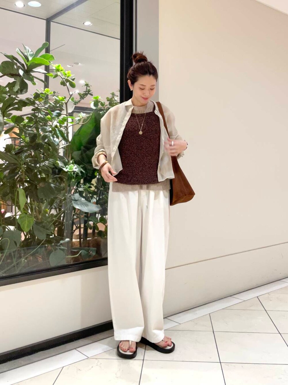 イエロー系のニット/セーター、ホワイト系のその他パンツ、ブラウン系のキャミソールを着用したレディースの春コーディネートの1枚目の写真
