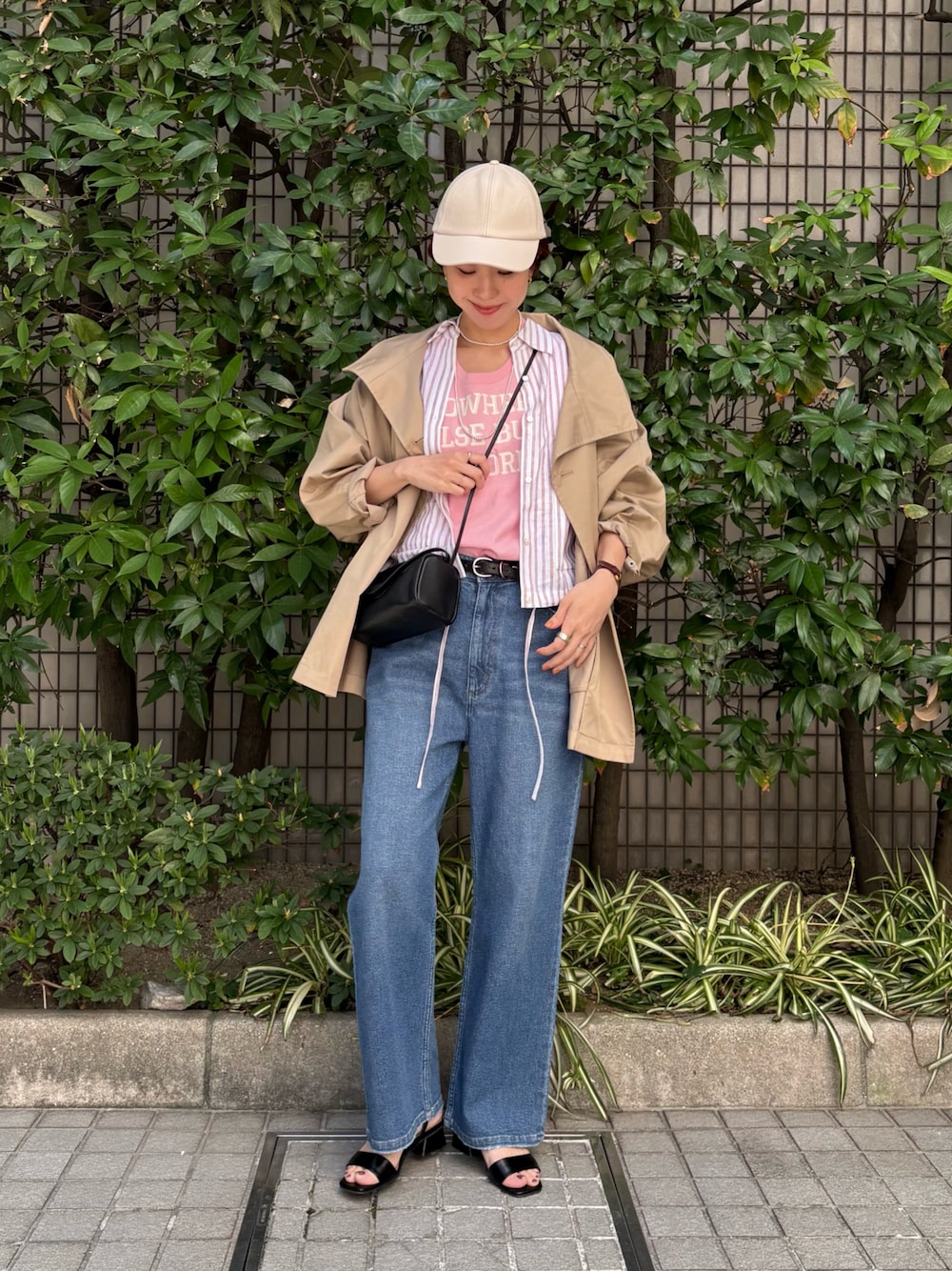 レッド系のシャツ/ブラウス、ベージュ系のトレンチコート、ブルー系のデニムパンツを着用したレディースの春コーディネートの1枚目の写真