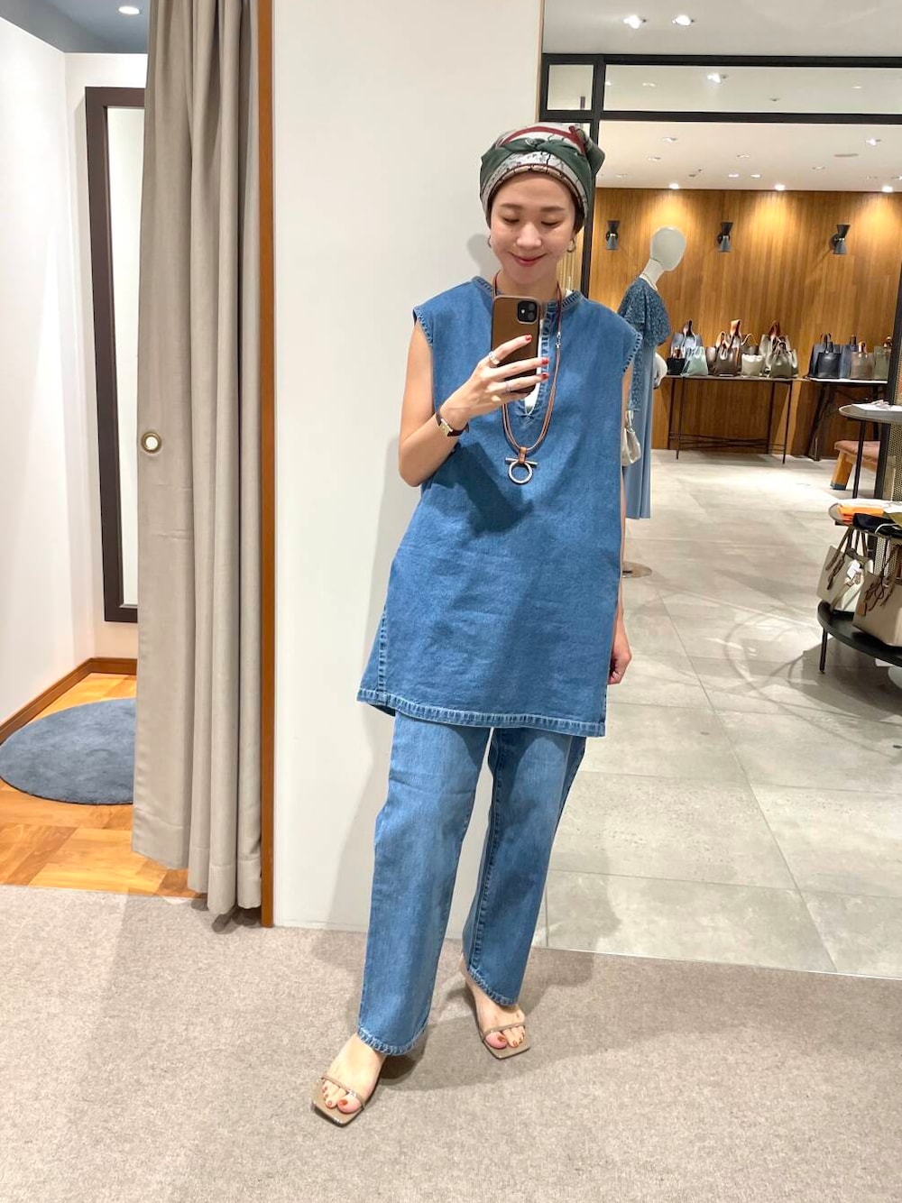 ホワイト系のタンクトップ、ブルー系のベスト、ブルー系のデニムパンツを着用したレディースの夏コーディネートの1枚目の写真