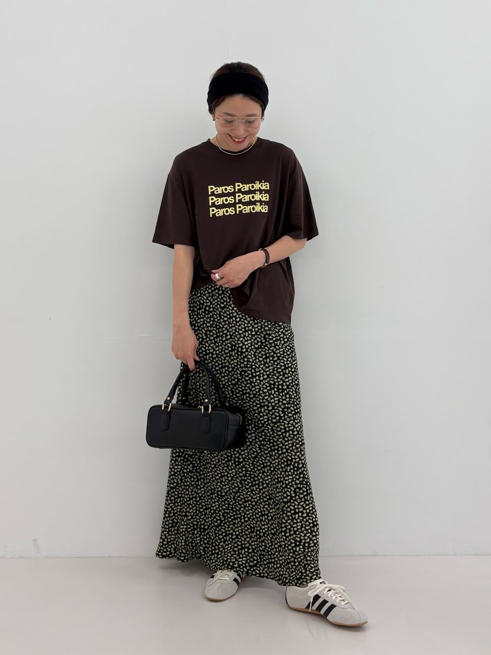 ブラウン系のTシャツ/カットソー、イエロー系のスカート、ブラック系のハンドバッグを着用したレディースの夏コーディネートの1枚目の写真