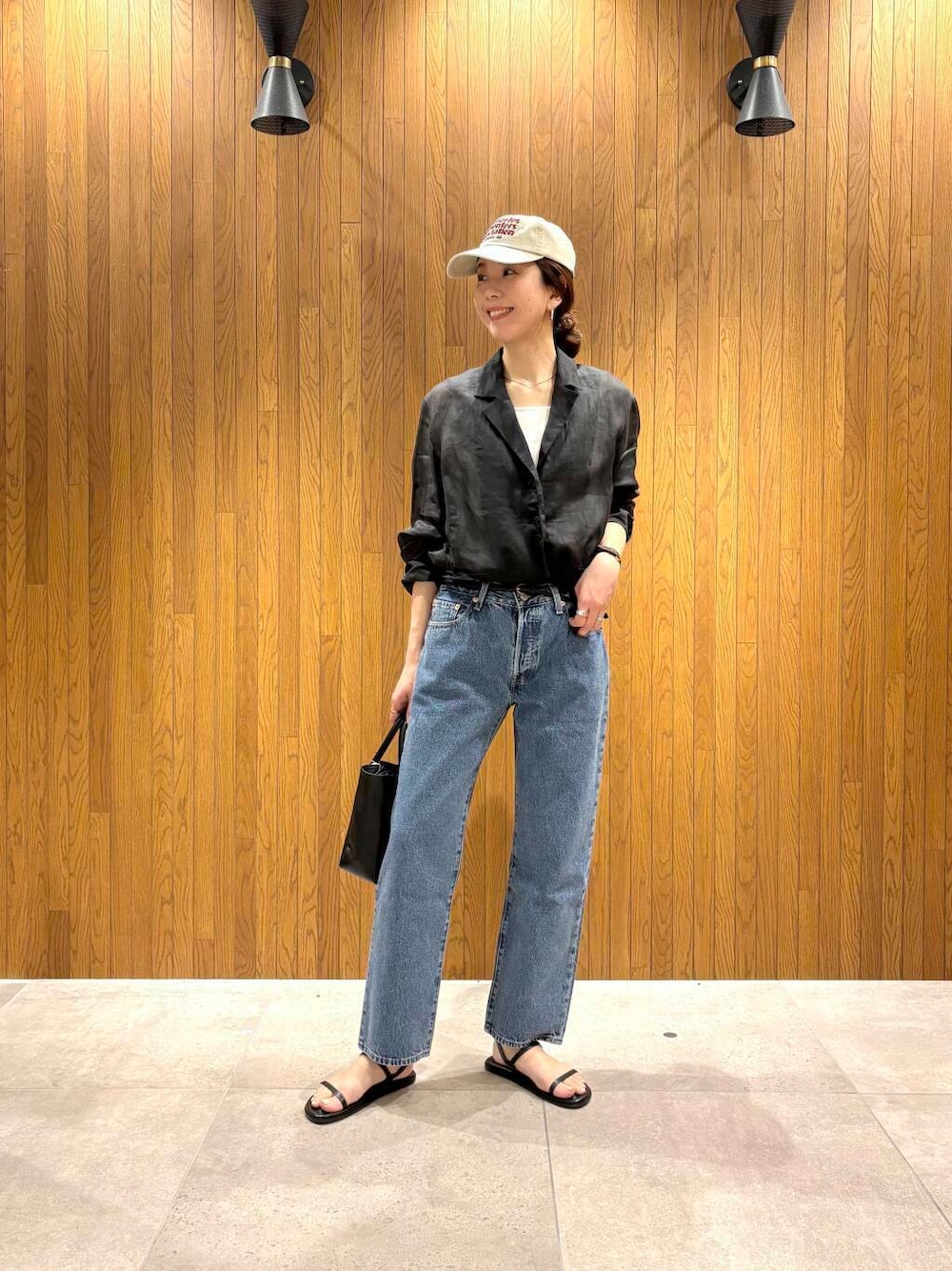 ブラック系のその他アウター、ブルー系のデニムパンツ、ベージュ系のキャップを着用したレディースの春コーディネートの1枚目の写真