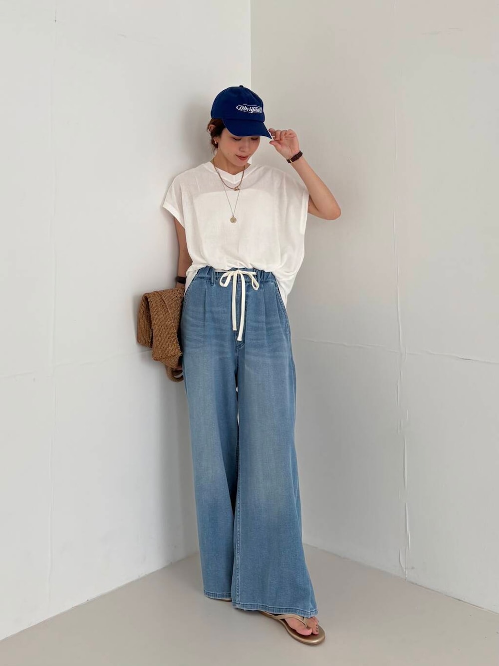 ホワイト系のキャミソール、ブルー系のデニムパンツ、ホワイト系のニット/セーターを着用したレディースの夏コーディネートの1枚目の写真