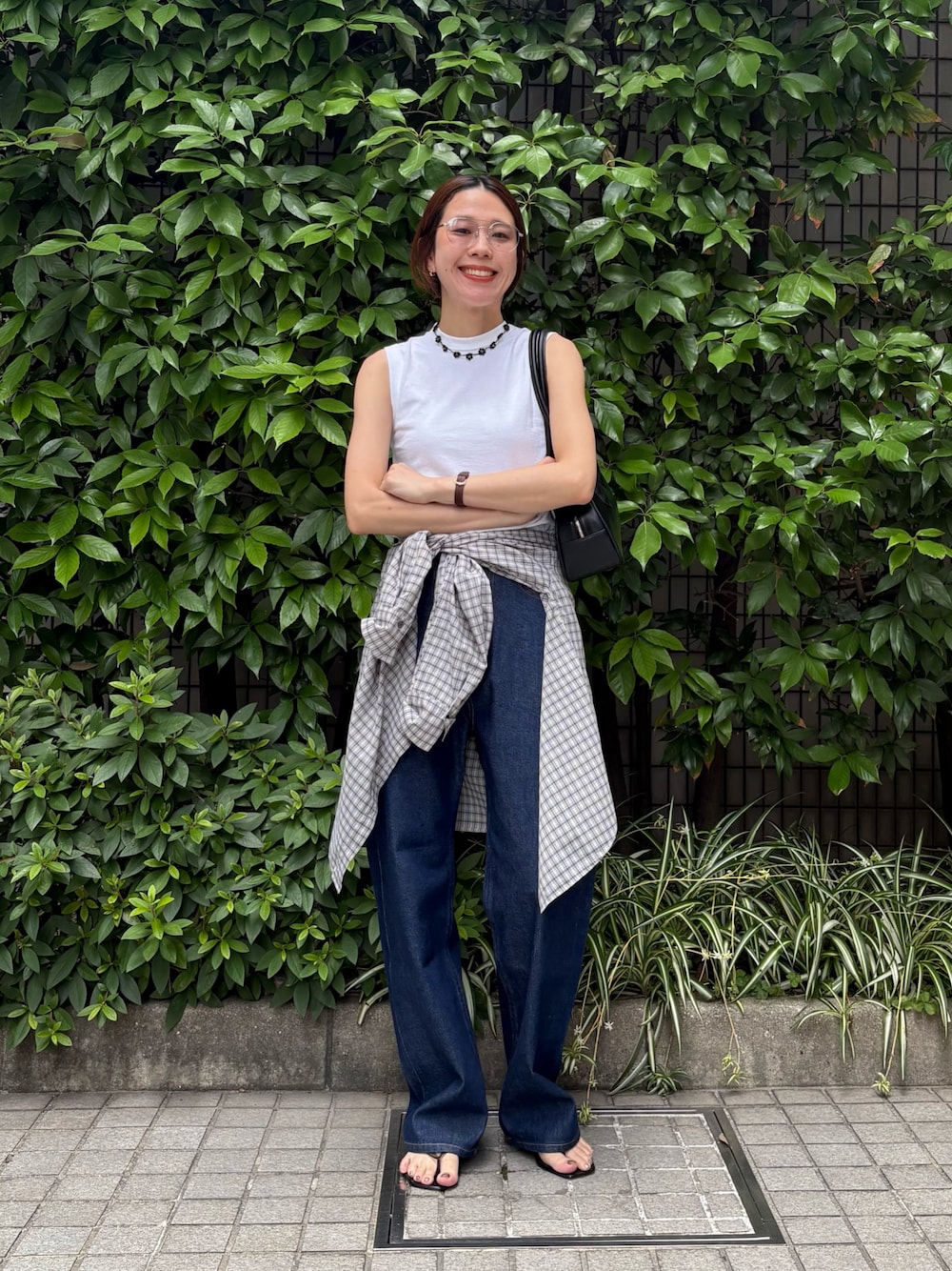 ブルー系のデニムパンツ、ブラック系のショルダーバッグ、ホワイト系のタンクトップを着用したレディースの夏コーディネートの1枚目の写真