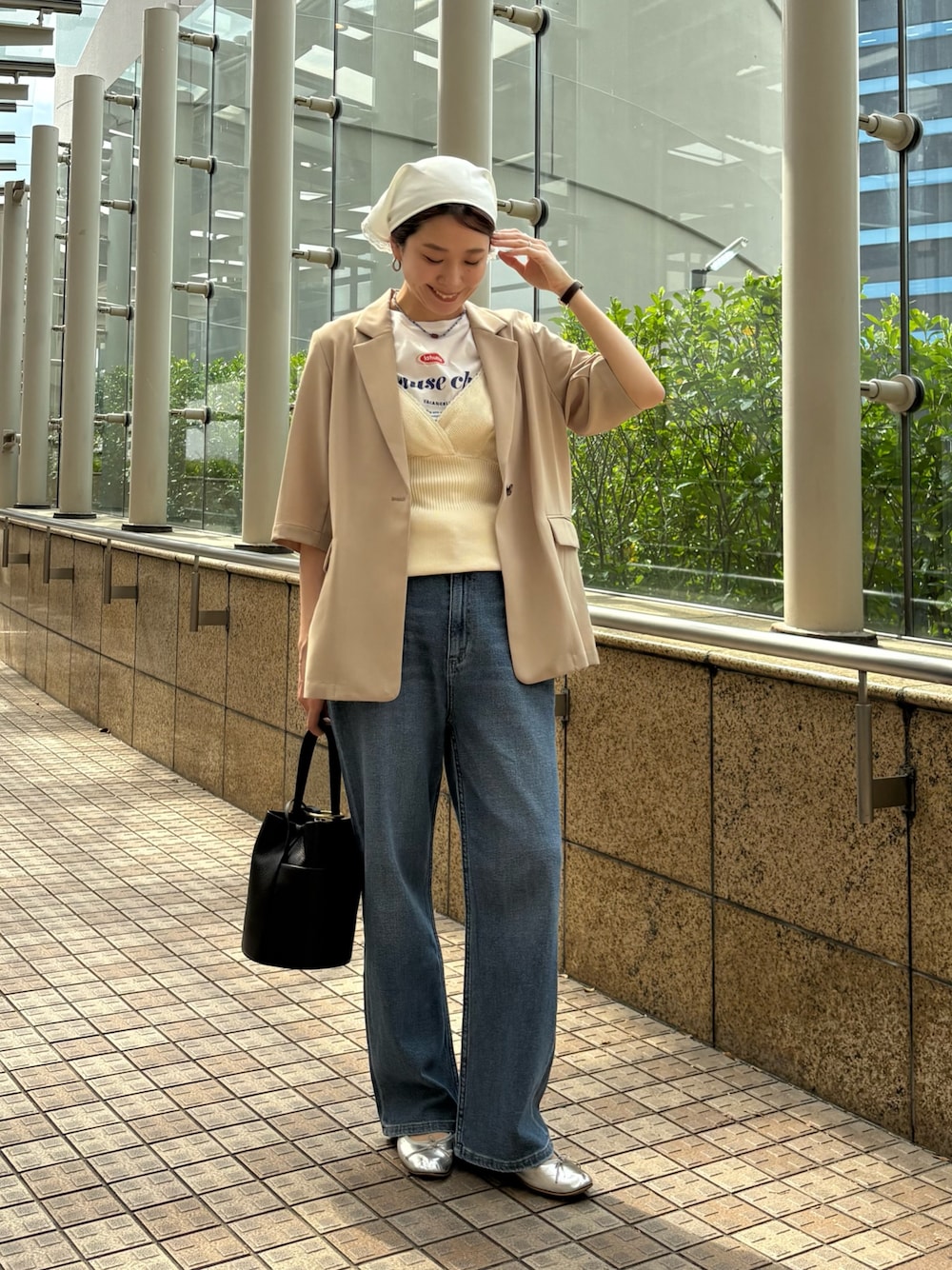 ブルー系のデニムパンツ、ベージュ系のその他アウター、ブラック系のハンドバッグを着用したレディースの春コーディネートの1枚目の写真