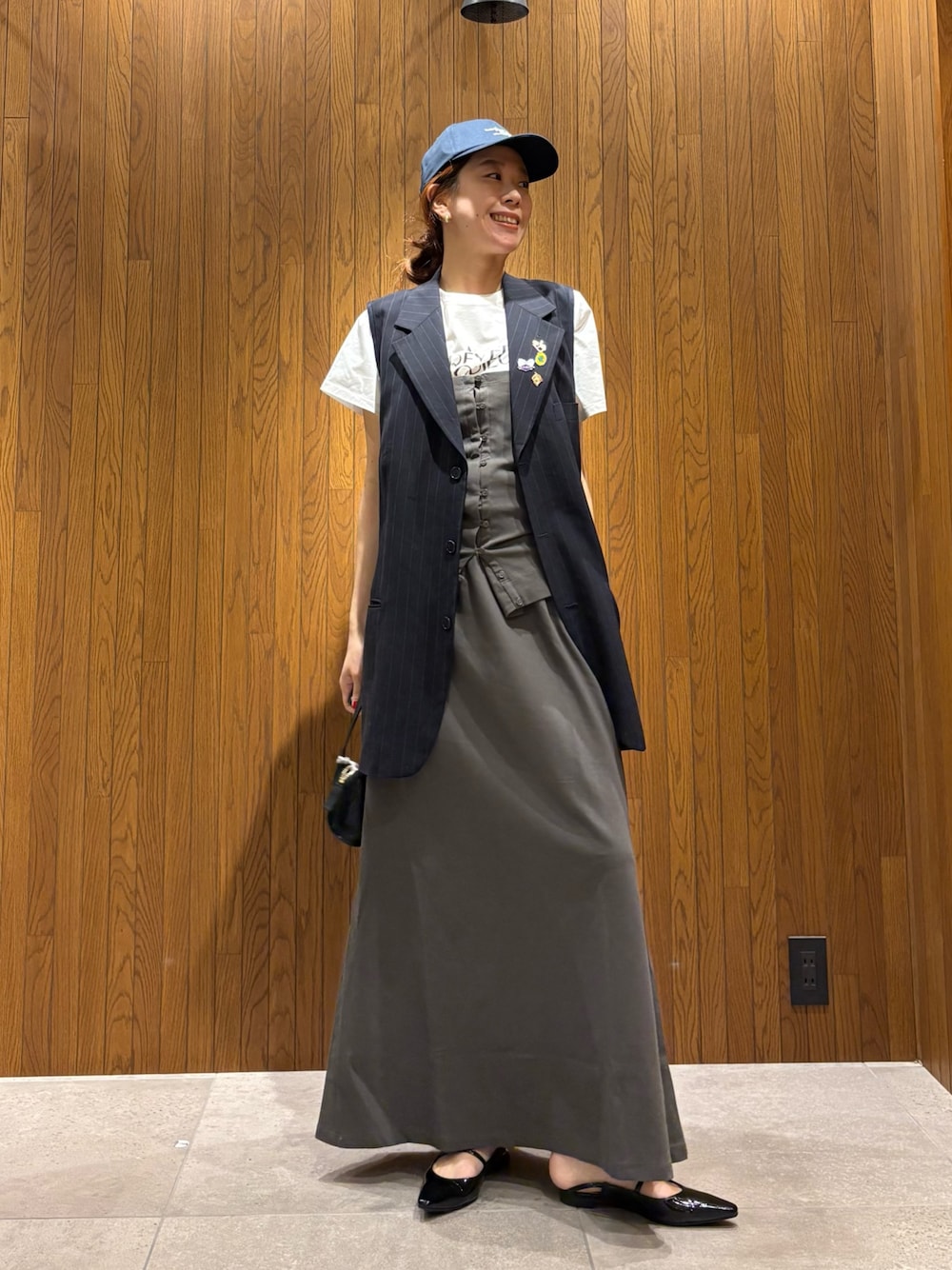 グレー系のスカート、その他のTシャツ/カットソー、ブラック系のハンドバッグを着用したレディースの春コーディネートの1枚目の写真