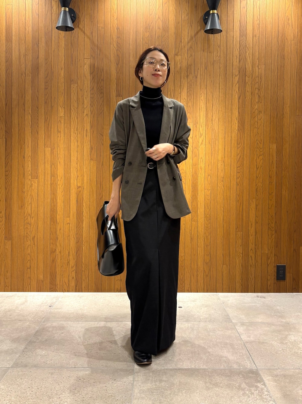 ブラック系のスカート、ブラック系のニット/セーター、ブラック系のハンドバッグを着用したレディースの秋コーディネートの1枚目の写真