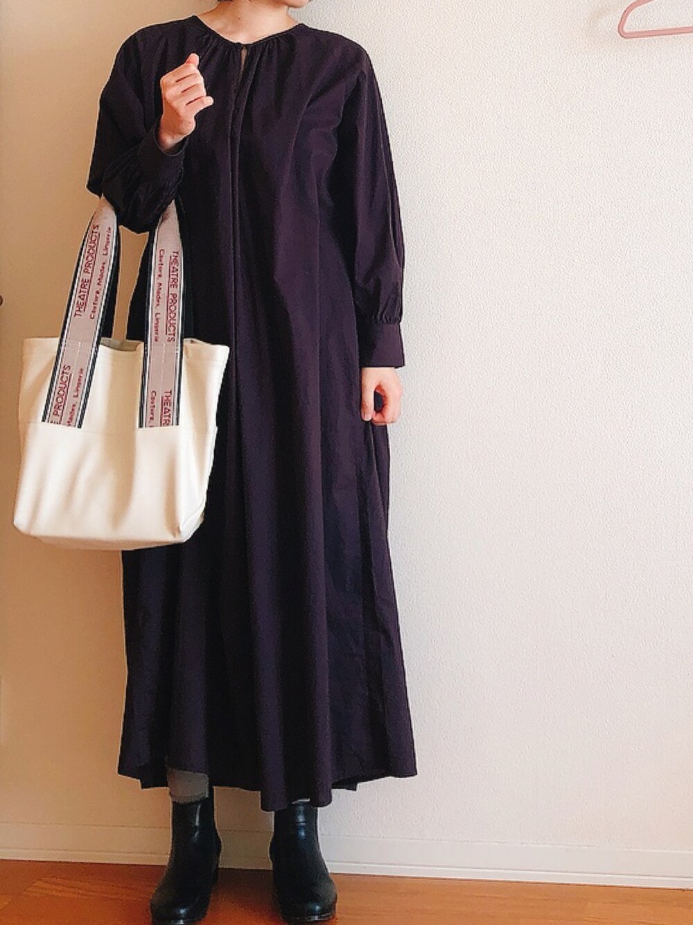 ホワイト系のトートバッグ、ブラック系のワンピース、ブラック系のブーツを着用したレディースの秋コーディネートの1枚目の写真