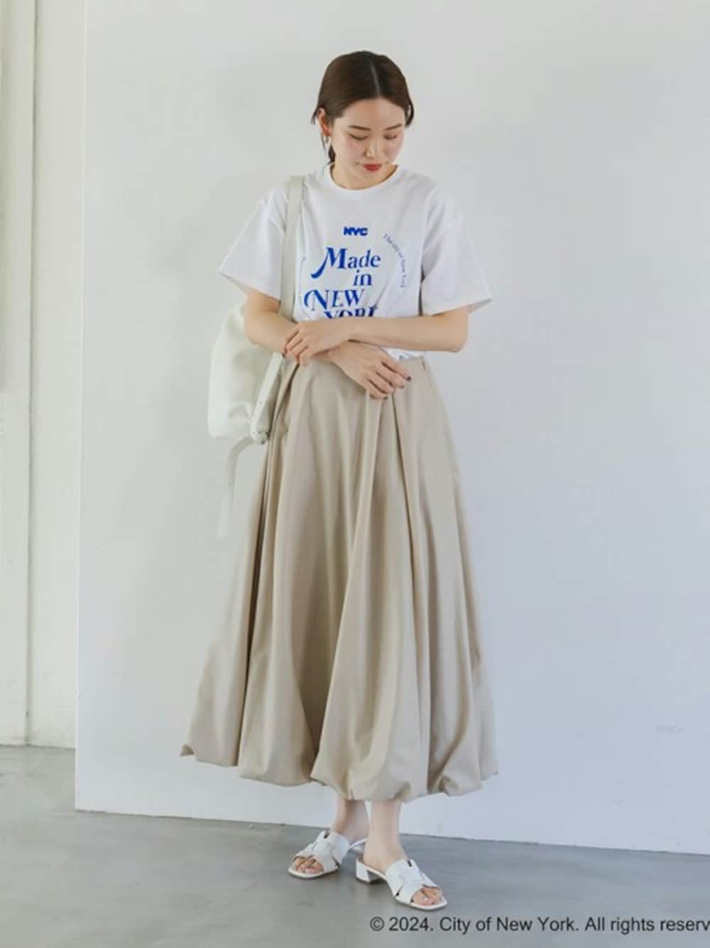 ホワイト系のTシャツ/カットソー、ベージュ系のスカート、ホワイト系のサンダルを着用したレディースの春コーディネートの1枚目の写真