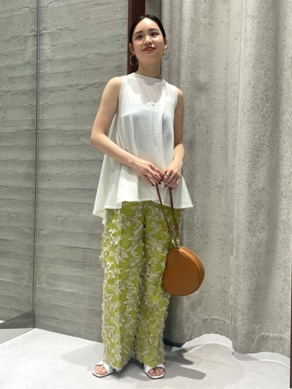 ホワイト系のTシャツ/カットソー、グリーン系のスラックス、イエロー系のショルダーバッグを着用したレディースの春コーディネートの1枚目の写真