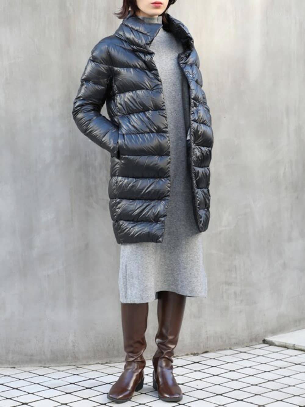 ブラック系のダウンジャケット/コート、グレー系のワンピース、ブラウン系のブーツを着用したレディースの秋コーディネートの1枚目の写真